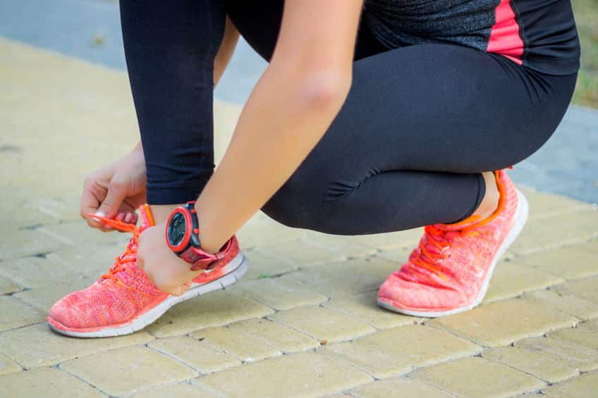 Young fitness girl ties up sneakers laces preparing for working